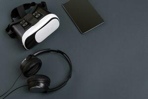 Virtual reality glasses and tablet with headphones on a gray background. Top view photo