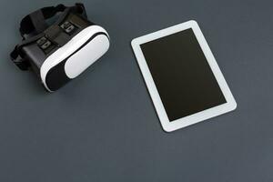 Virtual reality glasses and tablet on a gray background. Top view photo