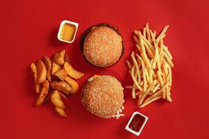 hamburguesa y papas fritas. hamburguesa y francés papas fritas en rojo papel caja. rápido comida en rojo antecedentes. foto