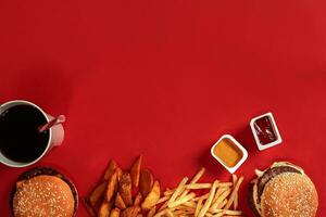 Fast food dish top view. Meat burger, potato chips and glass of drink on red background. Takeaway composition. photo