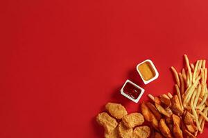 Nuggets and Chips. Nuggets and french fries in red paper box. Fast food on red background. photo