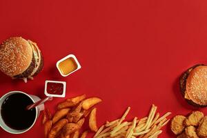 rápido comida plato parte superior vista. carne hamburguesa, patata papas fritas y vaso de bebida en rojo antecedentes. para llevar composición. foto