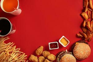 rápido comida plato parte superior vista. carne hamburguesa, patata papas fritas y vaso de bebida en rojo antecedentes. para llevar composición. foto