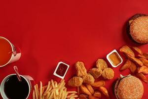 Fast food dish top view. Meat burger, potato chips and glass of drink on red background. Takeaway composition. photo