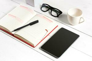 Stylish minimalistic workplace with tablet and notebook and glasses in flat lay style. White background. photo