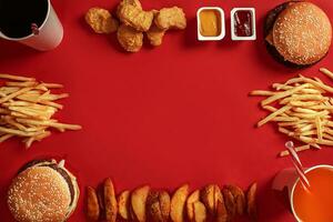 Two hamburgers and french fries, sauces and drinks on red background. Fast food. Top view, flat lay with copyspace photo