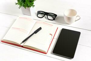 elegante minimalista lugar de trabajo con tableta y cuaderno y lentes en plano laico estilo. blanco antecedentes. foto