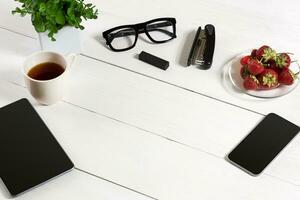 Modern workplace with digital tablet computer and mobile phone, cup of coffee and flower on white background. Top view photo