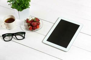 Flower pot, glasses, tablet on white desktop photo