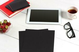 Stylish minimalistic workplace with tablet and notebook and glasses in flat lay style. White background. photo