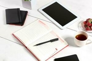 Stylish minimalistic workplace with tablet and notebook and glasses in flat lay style. White background. photo