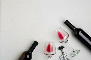 Glasses and bottles of red and white wine on white background from top view photo