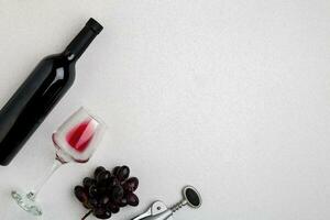 Overhead angled view of a large bottle of red wine, drinking glass on white background photo