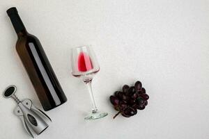 Overhead angled view of a large bottle of red wine, drinking glass on white background photo