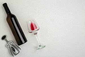 Overhead angled view of a large bottle of red wine, drinking glass on white background photo