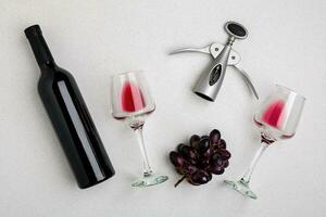 Wine, glasses and corkscrew over white background. Top view photo