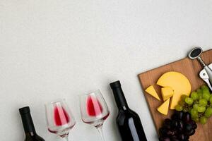 Glasses and bottles of red and white wine on white background from top view photo