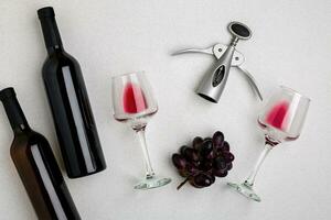 Glasses and bottles of red and white wine on white background from top view photo