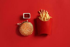 hamburguesa y papas fritas. hamburguesa y francés papas fritas en rojo papel caja. rápido comida en rojo antecedentes. foto