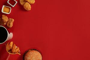 Concept of mock up burger, potatoes, sauce, chicken nuggets and drink on red background. Copy space for text and logo. photo