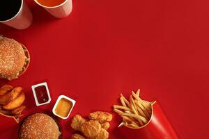 Fast food dish top view. Meat burger, potato chips and glass of drink on red background. Takeaway composition. photo