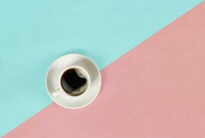 A cup of black coffee on blue and pink background. View from above. photo
