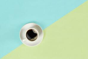 A cup of black coffee on blue and yellow background. View from above. photo