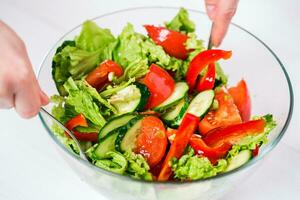 Young woman dressing vegetable salad with olive oil on a white background photo