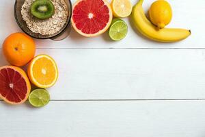 Fresh fruits with tape measure over white wooden background. Top view photo