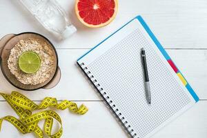 Fresh fruits with tape measure over white wooden background. Top view photo