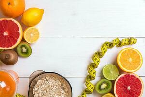 Fresh fruits with tape measure over white wooden background. Top view photo