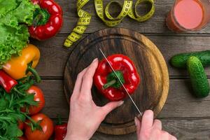 Female hands cutting pepper at table, top view photo