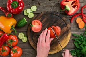 Female hands cutting tomato at table, top view photo