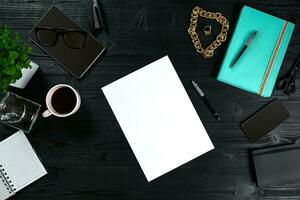 Flat lay, top view office table desk frame. Workspace with clean sheet of paper, mint diary and mobile device on dark background. photo