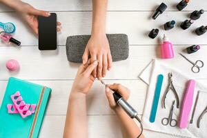 Closeup shot of a woman in a nail salon receiving a manicure by a beautician with nail file. Woman getting nail manicure. photo