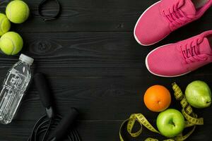 Athlete's set with female clothing and bottle of water on dark background photo