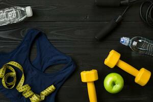 Athlete's set with female clothing and bottle of water on dark background photo