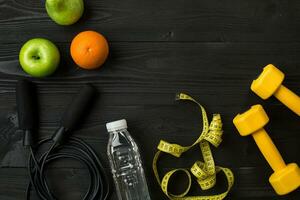 Athlete's set with female clothing, sneakers and bottle of water on dark background photo