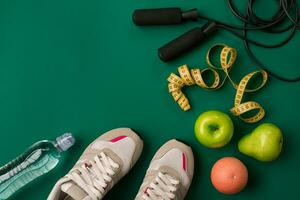 Workout plan with fitness food and equipment on green background, top view photo