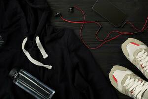 Athlete's set with female clothing, sneakers and bottle of water on dark background photo