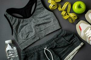 Athlete's set with female clothing and bottle of water on dark gray background photo