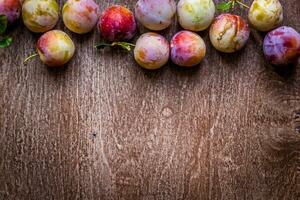 Fresh juicy plums on a wooden background photo