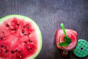 Watermelon smoothie and a half of fresh watermelon on dark wooden background. Flat lay or top view. photo