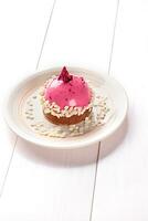 Small cake with different stuffing on a white plate. White wooden table. photo
