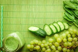 Ingredients for Green detox smoothie. Spinach, grape, cucumber on green background photo