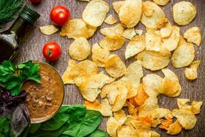 Potato chips with dipping sauce on a wooden table. Unhealthy food on a wooden background. photo