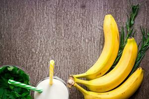 Banana smoothie and fresh banana on wooden table. photo