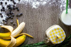 Banana smoothie and fresh banana on wooden table. photo