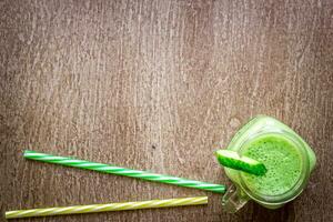 Glass of spinach juice on wooden background photo