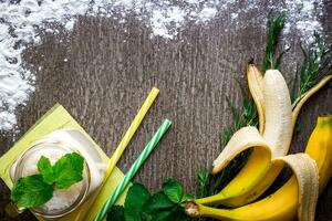 Banana smoothie and fresh banana on wooden table. photo